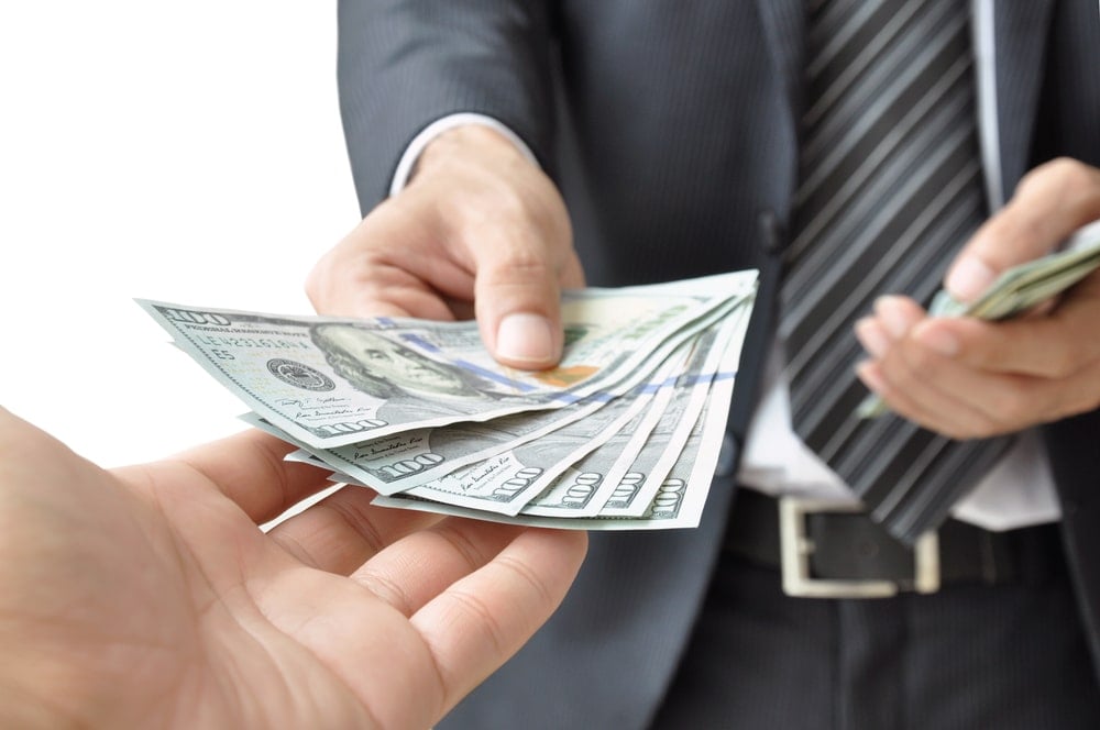 an image of a man handing out hundred dollar bills