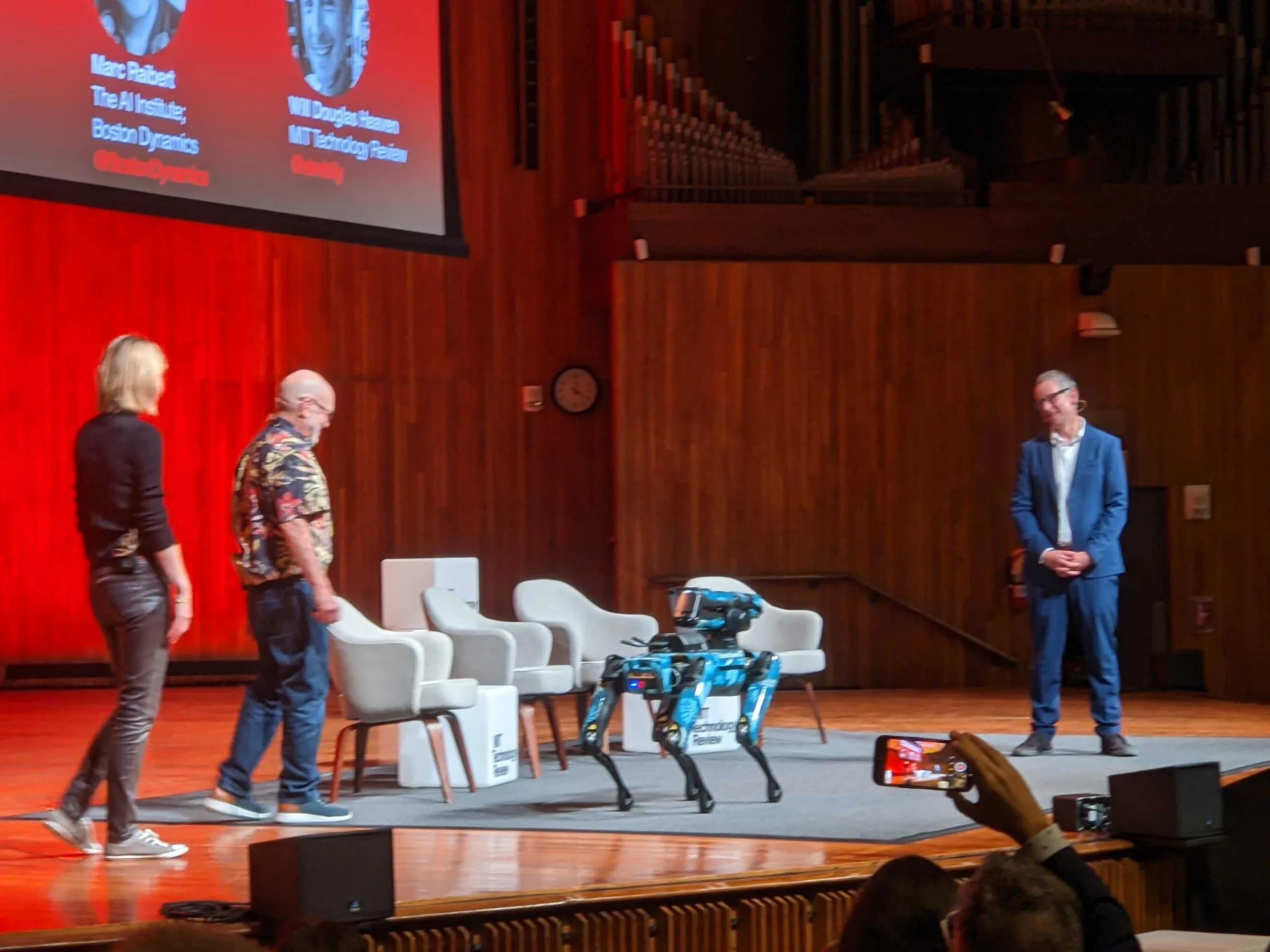 The AI Institute's Marc Raibert, Kat Darling, and "Atlas" standing on the stage at MIT's 2023 EmTech conference